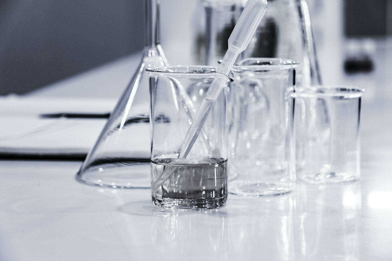 Clear laboratory beakers and a pipette on a white bench